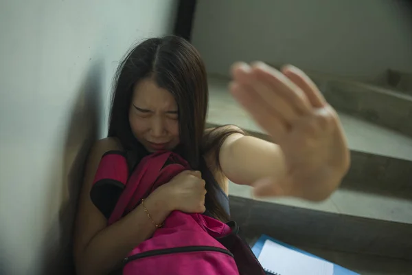 Молодая красивая депрессивная азиатская студентка японского колледжа, сидящая на лестнице, жертва насилия, чувствует себя испуганной и одинокой, когда тебя преследуют и запугивают. — стоковое фото