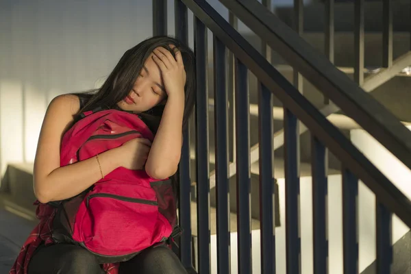 Joven hermosa deprimida asiática japonesa estudiante universitaria sentada en la escalera víctima de abuso sintiéndose asustada y sola siendo acosada y acosada —  Fotos de Stock