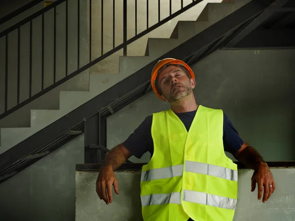 蓝领工作生活方式。年轻迷人和疲惫的建筑工人在建筑工地的头盔和背心的肖像看起来疲惫和紧张 — 图库照片