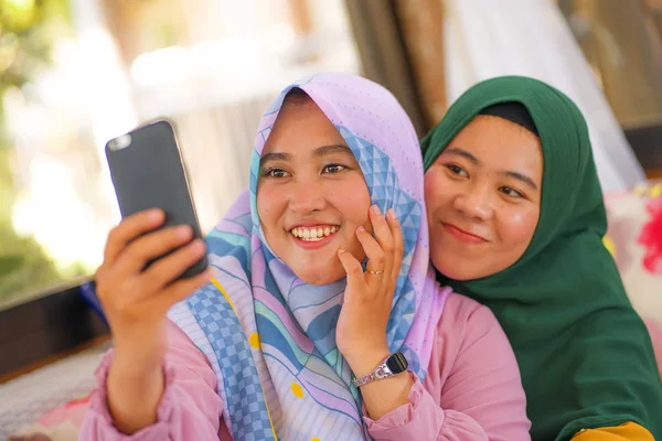 Мусульманские девушки-подростки селфи - симпатичные азиатские индонезийские девушки в традиционном исламском шарфе хиджаба, делающие селфи вместе — стоковое фото