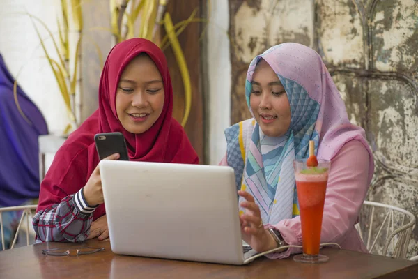 geleneksel İslami başörtüsü başörtüsü genç mutlu ve güzel Müslüman öğrenci kadın dizüstü bilgisayar ile kafede birlikte çalışan online iş konuşma