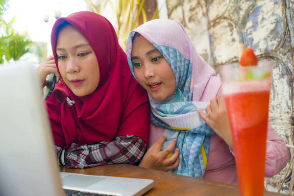 Young happy and beautiful Muslim student women in traditional Islamic hijab head scarf  talking online business working together at cafe with laptop computer — Stock Photo, Image