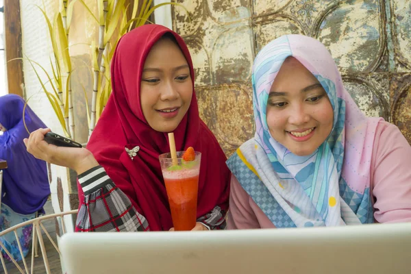 Jovens mulheres estudantes muçulmanas felizes e bonitas no tradicional lenço de cabeça hijab islâmico falando negócios on-line trabalhando juntos no café com computador portátil — Fotografia de Stock