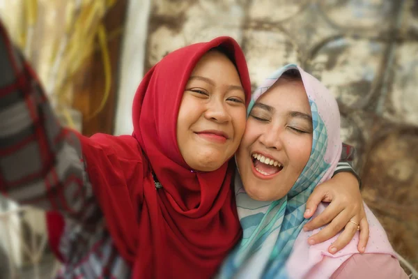 快乐和漂亮的亚洲印尼女孩在传统的伊斯兰头巾采取自拍一起在咖啡馆的友谊和社交媒体概念的乐趣 — 图库照片