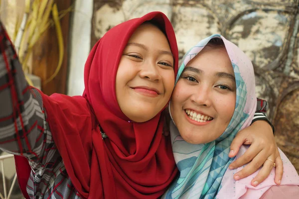 Chicas indonesias asiáticas felices y bonitas en la bufanda tradicional islámica de hiyab tomando selfie juntos divirtiéndose en la cafetería en concepto de amistad y redes sociales —  Fotos de Stock