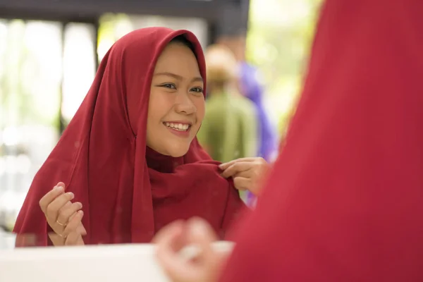 Espelho reflexo de jovem mulher muçulmana feliz e bonita no tradicional hijab ajustando lenço cabeça vermelha em conceito de beleza e moda sorrindo na expressão do rosto doce — Fotografia de Stock