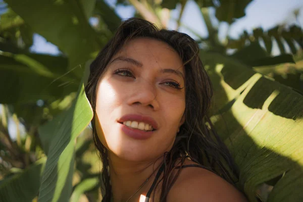 Young beautiful and happy Asian Indonesian woman in bikini posing between leaves of banana tree smiling natural isolated on exotic tropical background in Summer holiday — Stock Photo, Image