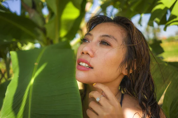 Young beautiful and happy Asian Indonesian woman in bikini posing between leaves of banana tree smiling natural isolated on exotic tropical background in Summer holiday — Stock Photo, Image