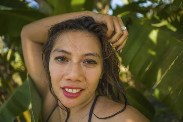 Young beautiful and happy Asian Indonesian woman in bikini posing between leaves of banana tree smiling natural isolated on exotic tropical background in Summer holiday — Stock Photo, Image