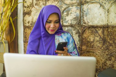 geleneksel başörtüsü genç güzel ve başarılı Asyalı kadın dizüstü bilgisayar ve cep telefonu online internet iş çalışan çalışan rahat ve mutlu