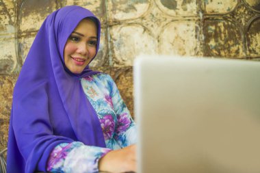 geleneksel Müslüman başörtüsü başörtüsü genç güzel ve başarılı Asyalı kadın online internet iş rahat ve mutlu çalışan dizüstü bilgisayar üzerinde çalışan