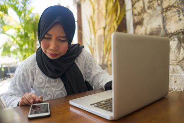  orta yaş Asyalı Endonezyalı Müslüman kadın geleneksel başörtüsü çalışma ev bahçesinde internet iş başarı online iş çalışan rahat çalışma