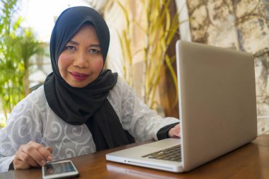  orta yaş Asyalı Endonezyalı Müslüman kadın geleneksel başörtüsü çalışma ev bahçesinde internet iş başarı online iş çalışan rahat çalışma