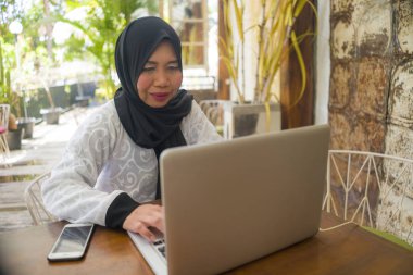  orta yaş Asyalı Endonezyalı Müslüman kadın geleneksel başörtüsü çalışma ev bahçesinde internet iş başarı online iş çalışan rahat çalışma