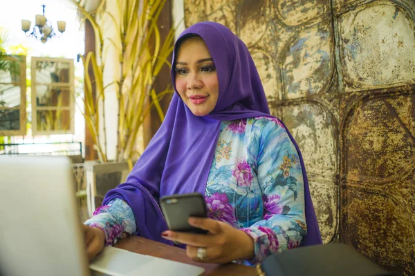 Jonge mooie en succesvolle Aziatische vrouw in traditionele hijab hoofd sjaal werken op laptop computer en mobiele telefoon Running online Internet Business ontspannen en gelukkig — Stockfoto