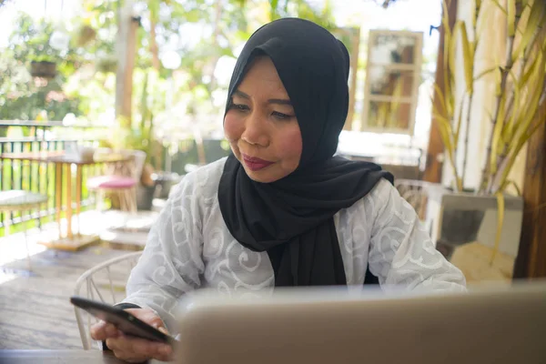 Middelbare leeftijd Aziatische Indonesische moslim vrouw in traditionele hijab hoofd sjaal werken ontspannen in Home Garden Running online business in Internet baan succes — Stockfoto