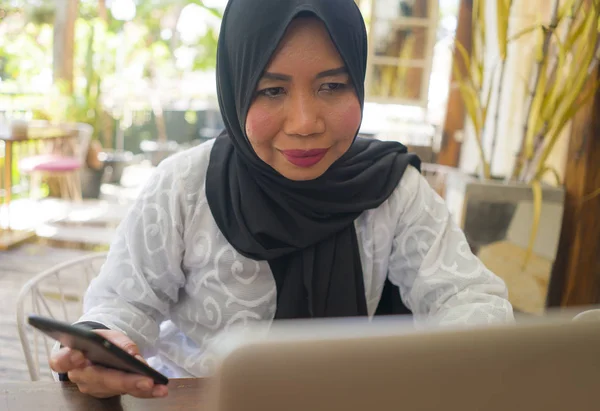 Idade média asiático indonésio muçulmano mulher no tradicional hijab cabeça cachecol trabalhando relaxado em casa jardim executando negócios on-line no sucesso do trabalho na internet — Fotografia de Stock