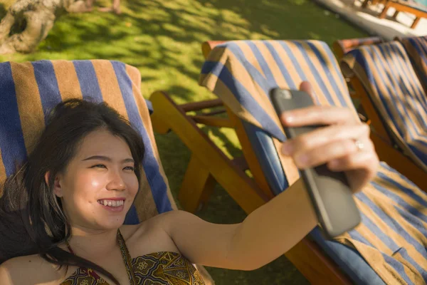 Joven hermosa y feliz turista asiática coreana mujer tomando selfie en tropical resort piscina hamaca sonriente despreocupado y natural en vacaciones de verano escapada — Foto de Stock