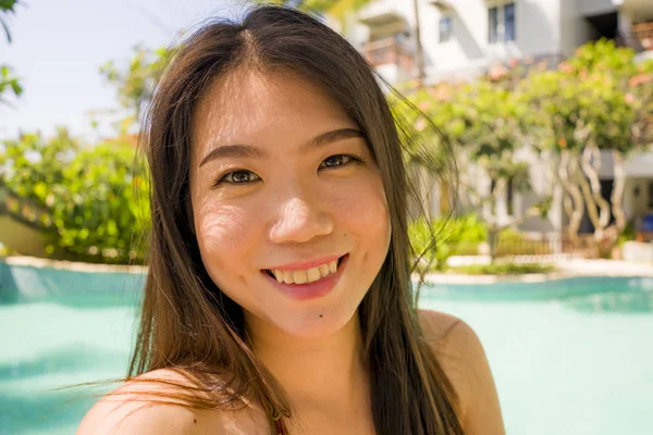 Молодая красивая и счастливая азиатская китайская туристка улыбается веселым и естественным селфи наслаждаясь летним отдыхом на роскошном тропическом курорте — стоковое фото