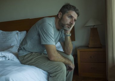 yatakta oturan yakışıklı adamın dramatik yaşam tarzı portresi üzgün düşünme ve depresyon ve anksiyete sorunu acı hissi 