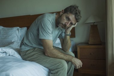 yatakta oturan yakışıklı adamın dramatik yaşam tarzı portresi üzgün düşünme ve depresyon ve anksiyete sorunu acı hissi 