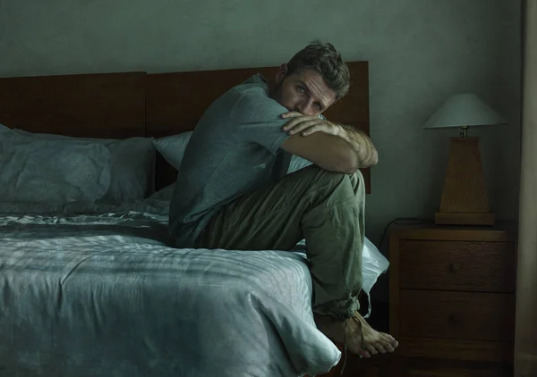 Atraktivní a smutný muž doma, který sedí na posteli a pláčí zoufalou trpící problém deprese — Stock fotografie
