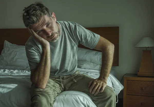 ベッドの上に悲しく座っている30代から40代のハンサムな男性のドラマチックなライフスタイルの肖像画が心配で絶望的なうつ病問題 — ストック写真