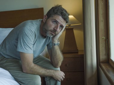 yatakta oturan yakışıklı adamın dramatik yaşam tarzı portresi üzgün düşünme ve depresyon ve anksiyete sorunu acı hissi 