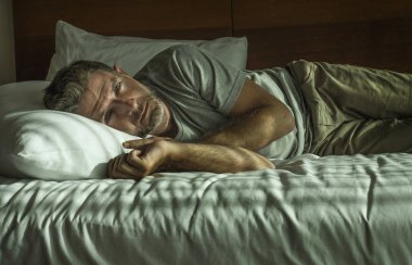 genç çekici üzgün ve depresif adam evde yatak odasında yatakta yatan dramatik yaşam tarzı portre düşünceli ve düşünceli duygu boğulmuş ve mutsuz