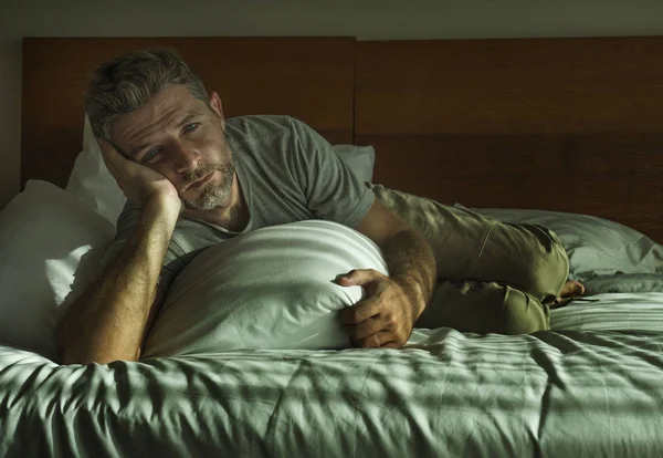 Dramatická životní styl portrét mladého půvabného smutného a depresivního muže ležícího na posteli doma v ložnici zamyšlený a pozorný a nešťastný — Stock fotografie