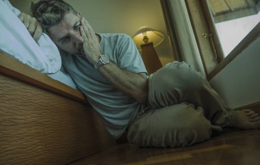 genç depresif ve umutsuz adam yatak yanında yatak katında oturan depresyon ve anksiyete duygu bunalmış ve çaresiz duygu acı