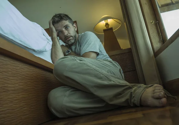年轻的沮丧和绝望的男人坐在卧室地板上床边遭受抑郁和焦虑感到不知所措和无助 — 图库照片