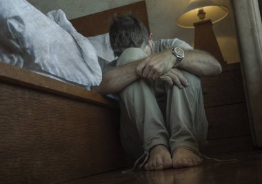 genç depresif ve umutsuz adam yatak yanında yatak katında oturan depresyon ve anksiyete duygu bunalmış ve çaresiz duygu acı