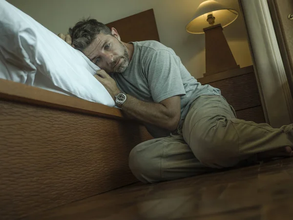 Giovane uomo depresso e disperato seduto sul pavimento della camera da letto accanto al letto che soffre depressione e ansia sentirsi sopraffatto e indifeso — Foto Stock