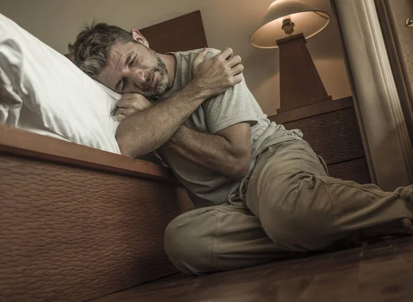 Pemuda tertekan dan putus asa duduk di lantai kamar tidur sebelah tempat tidur menderita depresi dan kecemasan merasa kewalahan dan tak berdaya — Stok Foto