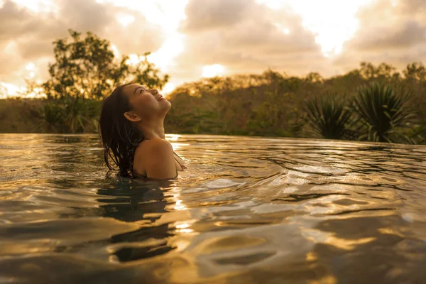 Vacaciones tropicales estilo de vida retrato de la joven hermosa y feliz mujer coreana asiática en bikini disfrutando de la puesta del sol en la increíble piscina infinita del complejo de la selva relajado — Foto de Stock