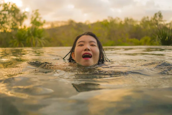 Feriados tropicais estilo de vida retrato de jovem bonita e feliz mulher asiática coreana de biquíni desfrutar do pôr do sol na incrível selva resort piscina infinita relaxado — Fotografia de Stock