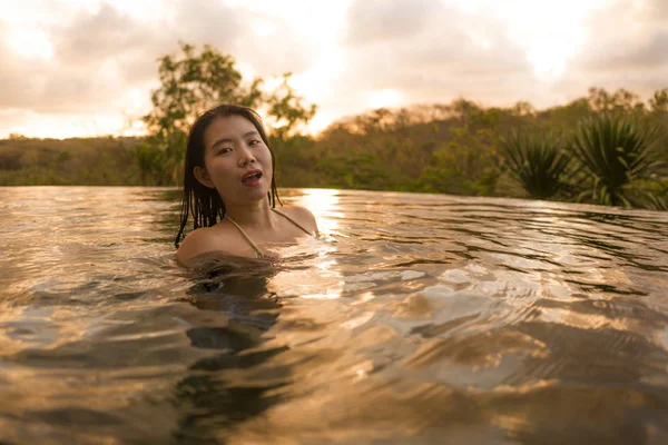 Feriados tropicais estilo de vida retrato de jovem bonita e feliz asiática chinesa mulher de biquíni desfrutar do pôr do sol em incrível selva resort infinito piscina relaxado — Fotografia de Stock