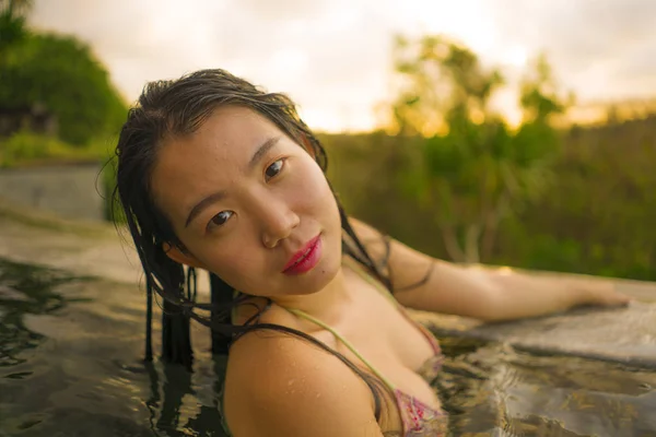 Vacaciones tropicales estilo de vida retrato de la joven hermosa y feliz mujer china asiática en bikini disfrutando de la puesta del sol en la increíble piscina infinita del complejo de la selva relajado — Foto de Stock