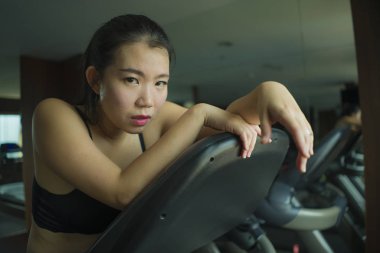 genç çekici ve uygun Asya Çinli kadın yorgun yüz ifadesi ile zor koşu bandı eğitim otel spor salonu veya fitness kulübü koşu egzersiz sırasında yorgun