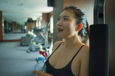 genç mutlu ve çekici Asyalı Koreli kadın vücut bakımı ve sağlıklı yaşam tarzı kavramı otel spor salonunda neşeli eğitim gülümseyerek fitness merkezi egzersiz sırasında içme suyu