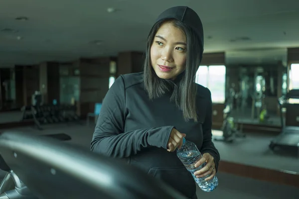 young happy and attractive Asian Korean woman drinking water during fitness center workout smiling cheerful training at hotel gym in body care and healthy lifestyle concept