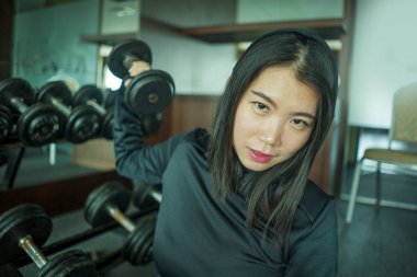spor kapüşonlu genç güzel ve mutlu Asyalı Koreli kadının doğal portre kaldırma egzersiz sırasında halter raf tarafından oturan fitness merkezinde serin poz