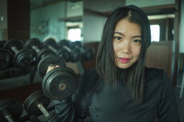 spor kapüşonlu genç güzel ve mutlu Asyalı Japon kadının doğal portre kaldırma egzersiz sırasında halter raf tarafından oturan fitness merkezinde serin poz