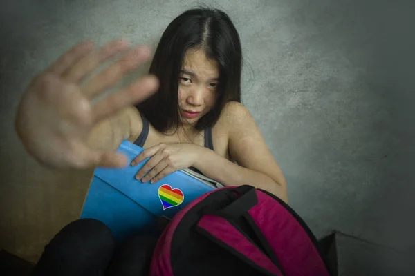És a szexuális megkülönböztetés elleni kampány tiszteletét. Fiatal gyönyörű depressziós és rémült ázsiai diák nő meleg zászlót a hátizsákjába — Stock Fotó
