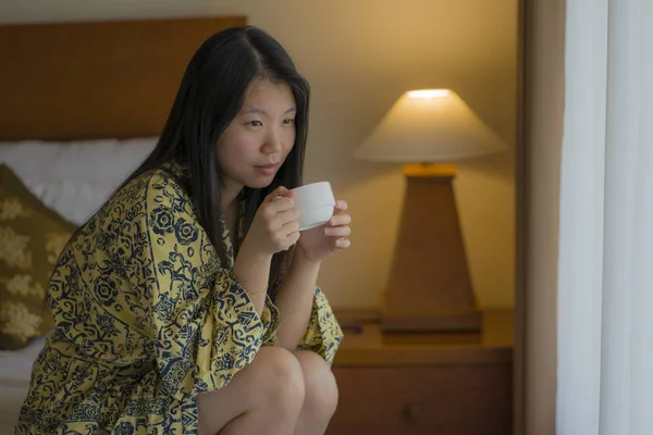 若い美しく自然なアジアの女性がベッドでコーヒーを飲む朝のライフスタイルの肖像画は、笑顔で陽気な景色を楽しんでリラックスした後にベッドで飲みます — ストック写真