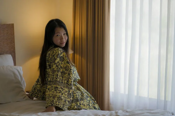 Утренний образ жизни портрет молодой красивой и естественной азиатской женщины, пьющей кофе в постели после пробуждения улыбаясь счастливой и веселой наслаждаясь видом расслабленной — стоковое фото