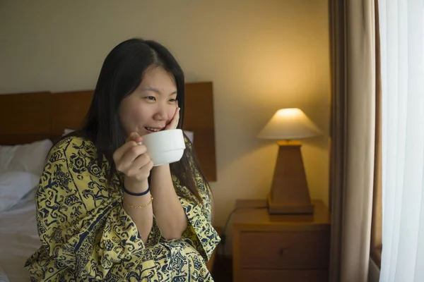 Morning Lifestyle portret van jonge mooie en natuurlijke Aziatische Koreaanse vrouw drinken koffie in bed na wakker glimlachend vrolijk en vrolijk genieten van het uitzicht ontspannen — Stockfoto