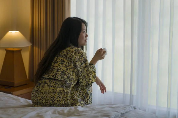 Утренний образ жизни портрет молодой красивой и естественной азиатской женщины, пьющей кофе в постели после пробуждения улыбаясь счастливой и веселой наслаждаясь видом расслабленной — стоковое фото