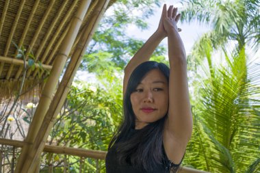 tropikal orman manzaralı güzel ahşap joglo stüdyoda yoga ve meditasyon egzersiz açık havada pratik genç doğal ve çekici Asyalı Çinli kadın